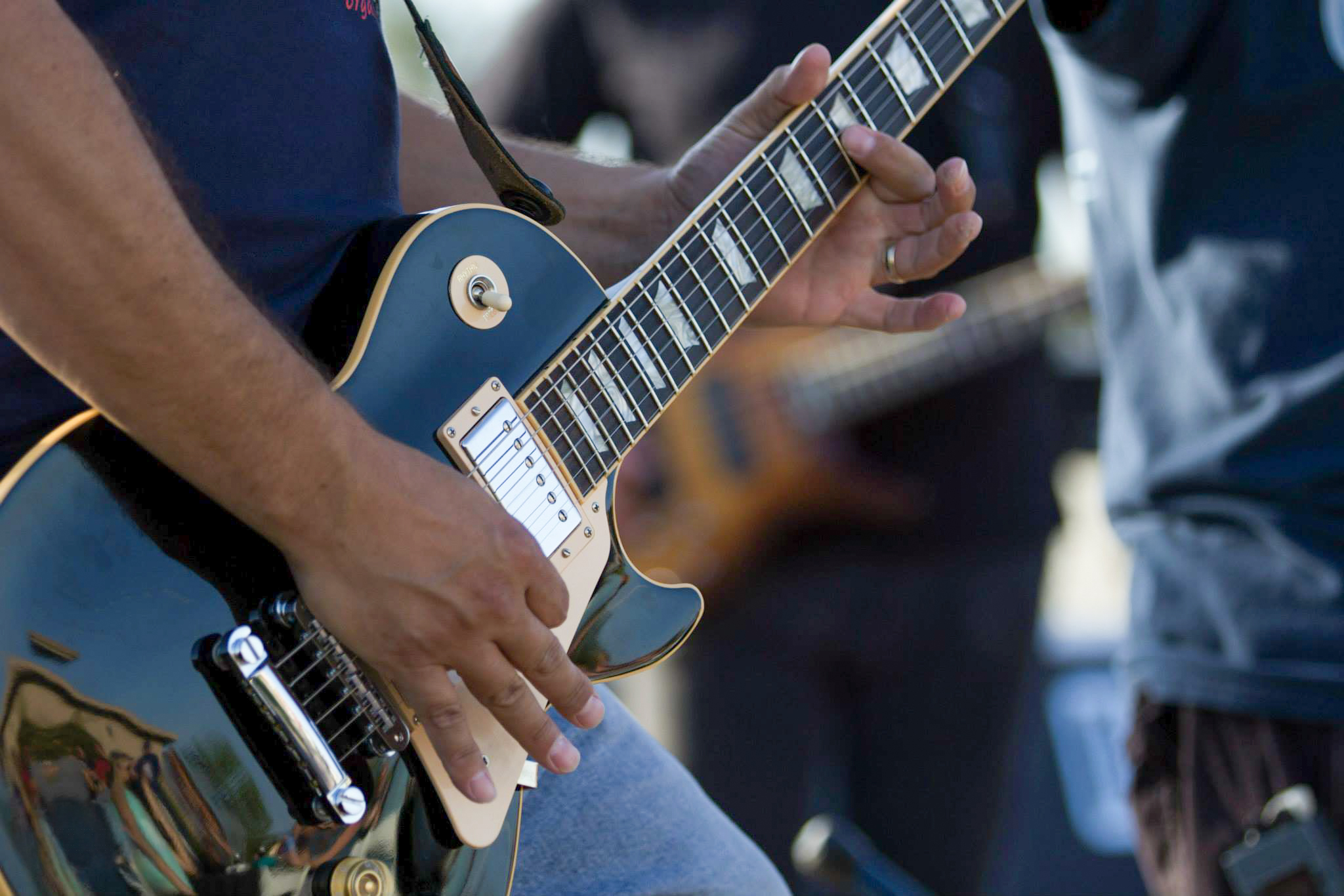 3D A closeup of a man playing a black Les Paul electric guitar at a concert, tyler media works, real estate photography