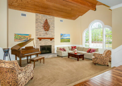 Bright living sunken living room with brick fireplace, a piano, wood rafter ceiling and view out the windows, tyler media works, real estate photography