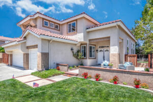Front of home with green grass and flowers, with a blue sky with clouds, tyler media works, real estate photography