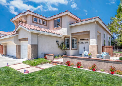 Front of home with green grass and flowers, with a blue sky with clouds, tyler media works, real estate photography