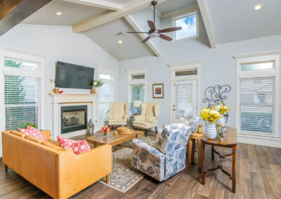 Living room with wood flooring, beige chairs, an orange leather loveseat, and a ceiling fan, tyler media works, real estate photography